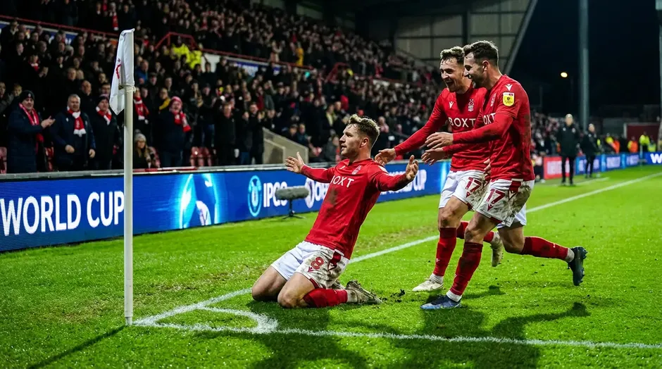 Joueurs de football en maillot rouge célébrant un but sur le terrain lors d'un match de la Coupe du Monde